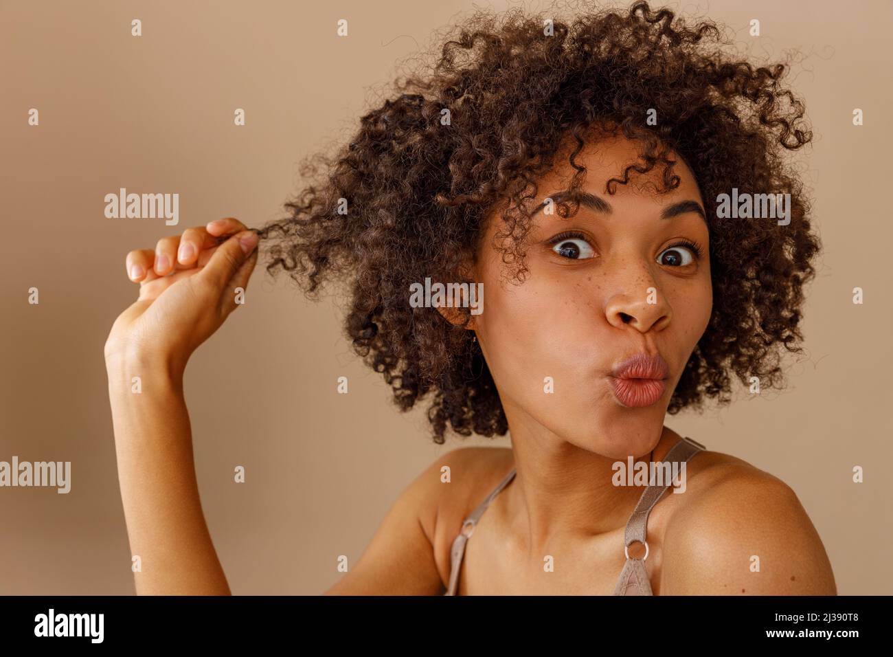 Stylish female model posing against beige wall Stock Photo