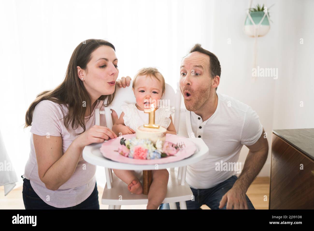 one year old little girl with daddy and mammy solemnize birthday Stock