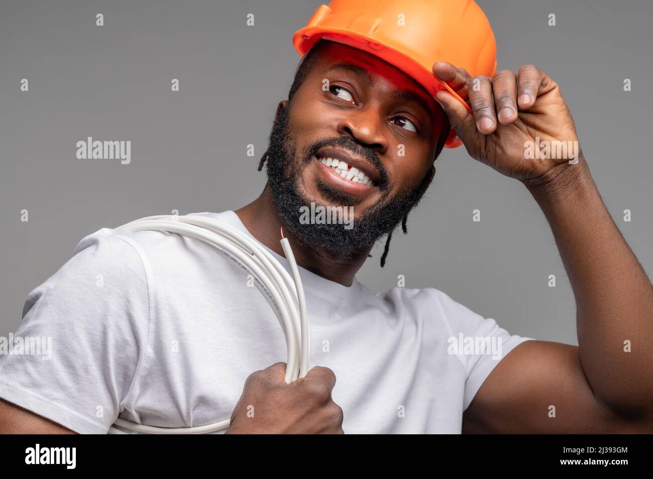Worker with a wrapped cable over the shoulder looking away Stock Photo