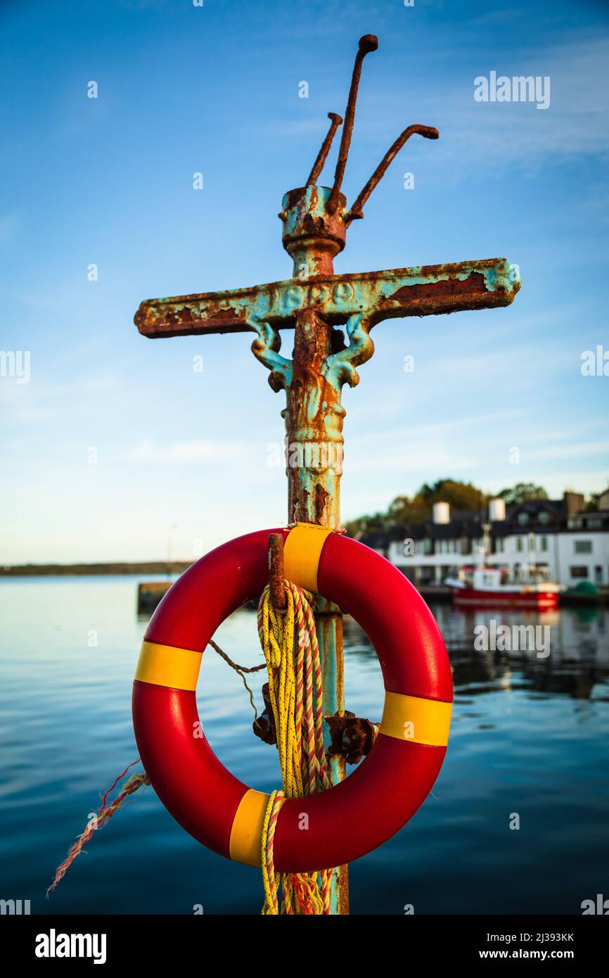 Life belt (life buoy) and rusting lamp-post at Roundstone harbour, Connemara, County Galway, Ireland. Stock Photo