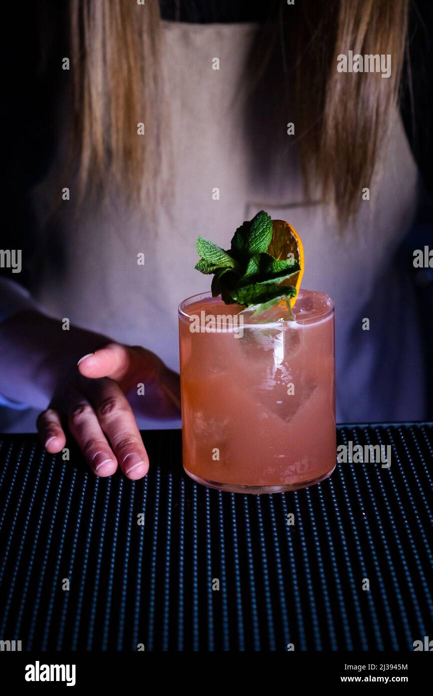A vertical shot of a woman grabbing a refreshing cocktail on the bar ...
