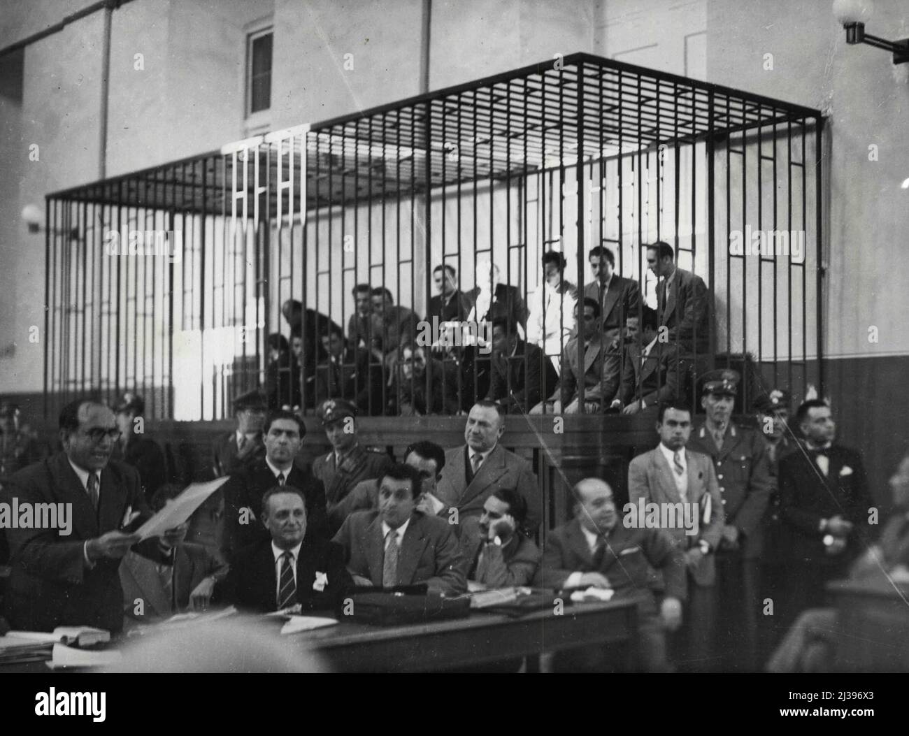 Gangsters Caged In Italy. Italian Gangsters are caged in a Naples police court October 31, as with their leader Giuseppe Lamarca (outside cage, Extreme Right, Dark suit) who is Managled, they face 51 charges of hold up, theft, blackmail and attacks on police. At left Dr. Luigi Caporale defence attorney for the men, reads a statement attorney for the men, reads a statement to the court. Lamarca has written his will, leaving a house to Caporale. This house, says the Bandit, will become a 'holy Shrine' visited by thousands of pilgrims during Holy Year. November 3, 1949. (Photo by Associated Stock Photo
