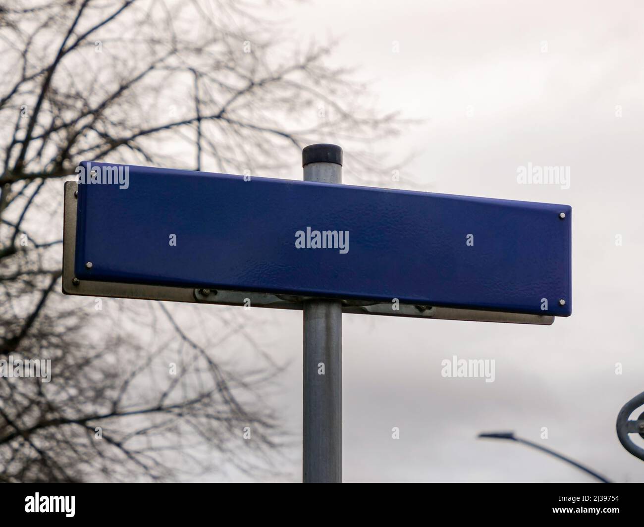 Empty blue street sign in Germany. Blank template to insert a road name. Metal plate without letters for the use as a mockup. Guide next to a way. Stock Photo