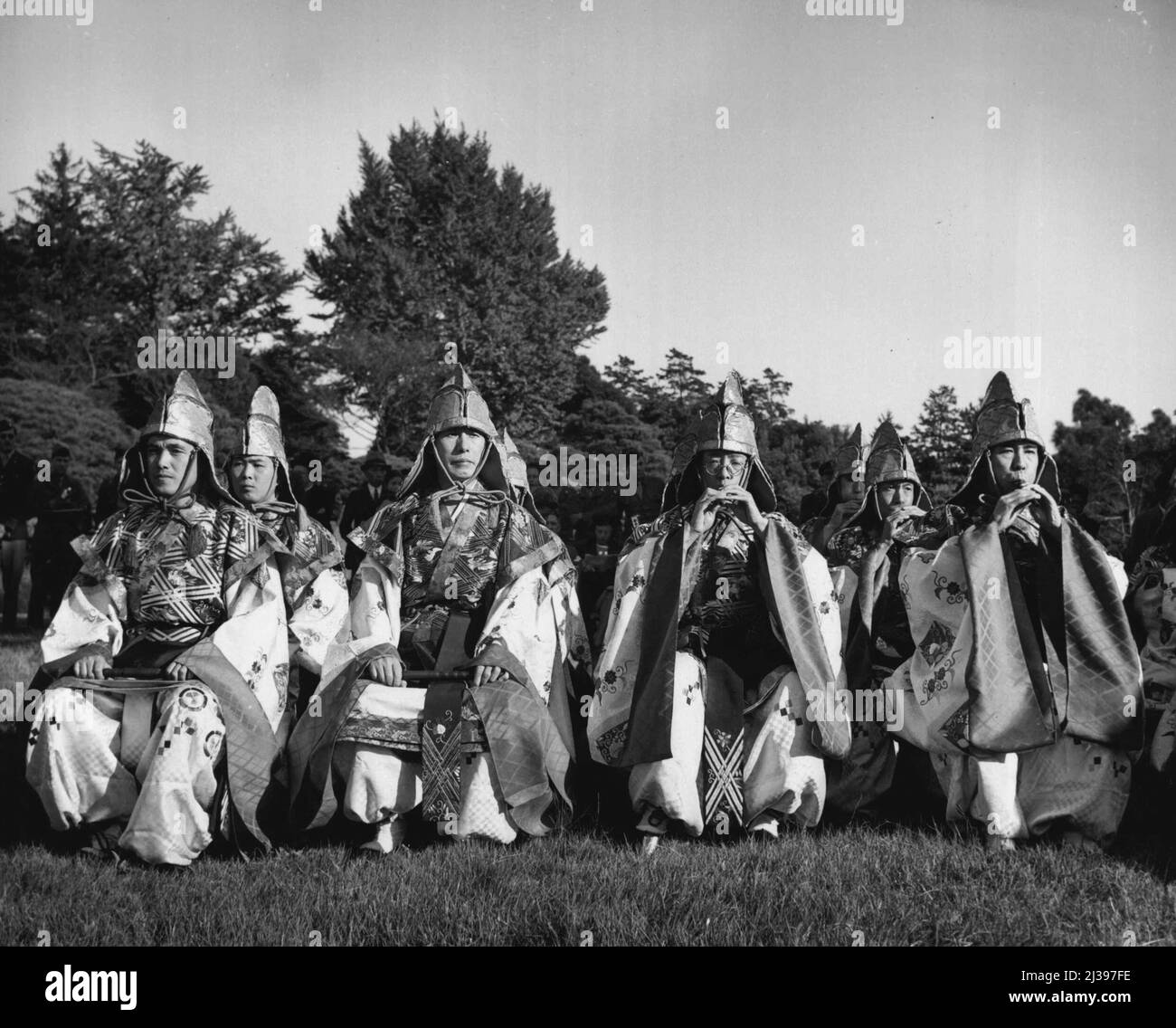 Exclusive Entertainment -- The bandsmen who accompany the performers in the Bugaku, an exclusive Japanese form of entertainment, wear hooded robes and play on reed pipes and flutes. For the first time this entertainment was presented to others than the royal family and high ranking officials. It was shown to members of the Allied Forces and civilian personnel at the Imperial Gardens here. November 11, 1946. (Photo by Wide World Photos). Stock Photo