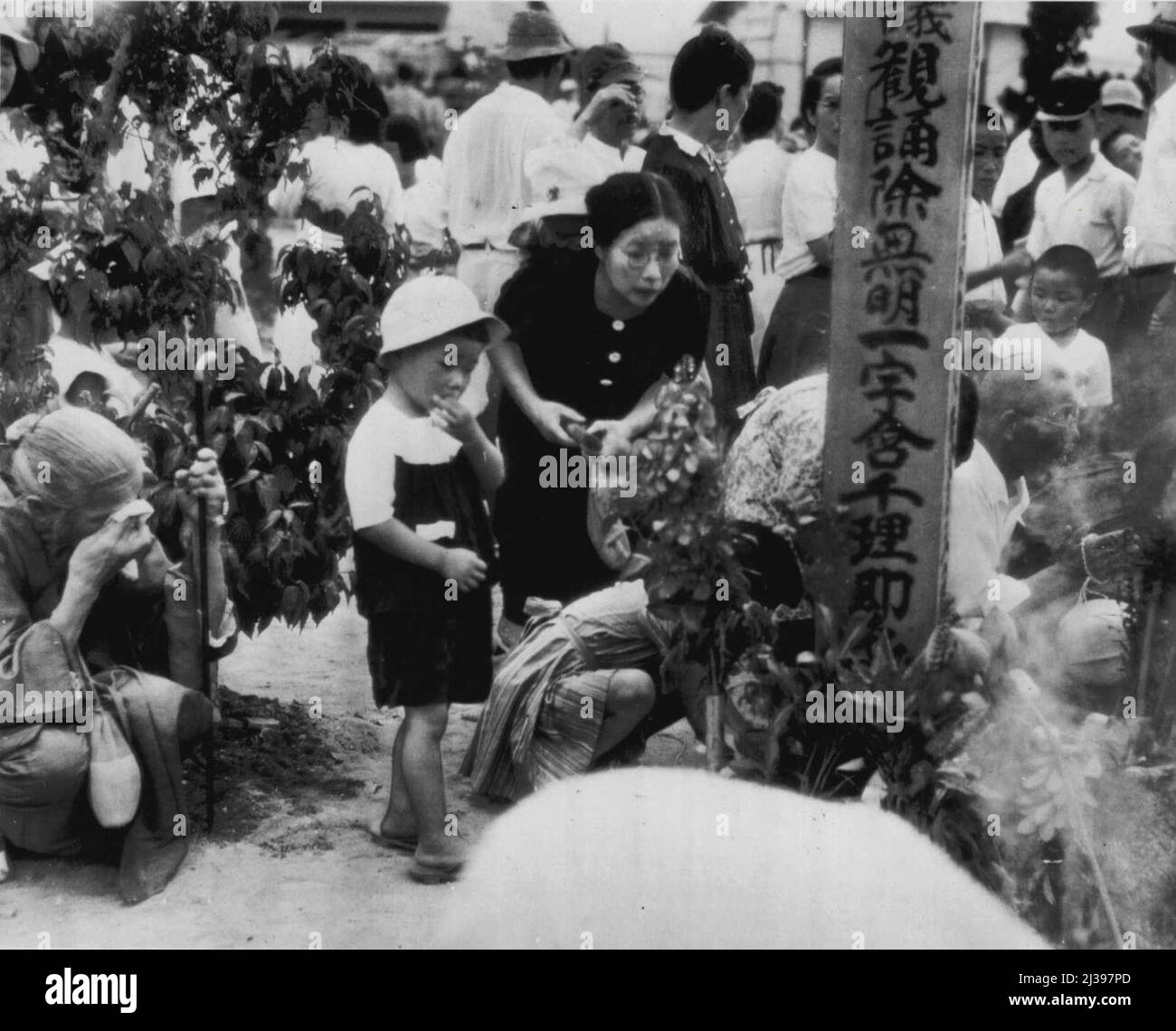 Flowers At Mass Grave Of Atom Bomb Victims -- Relatives and friends place flowers at the mass grave for thousands of unidentified victims of the atom bombing of Hiroshima Aug. 6, 1945. The second anniversary of the bombing was observed with a three-day peace festival field by survivors of the bombing. August 16, 1947. (Photo by AP Wirephoto). Stock Photo