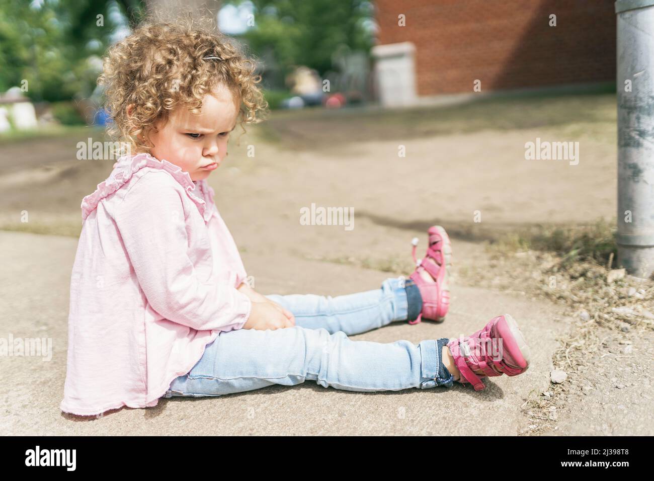 Young girl sitting on the floor at the school playground Stock Photo ...