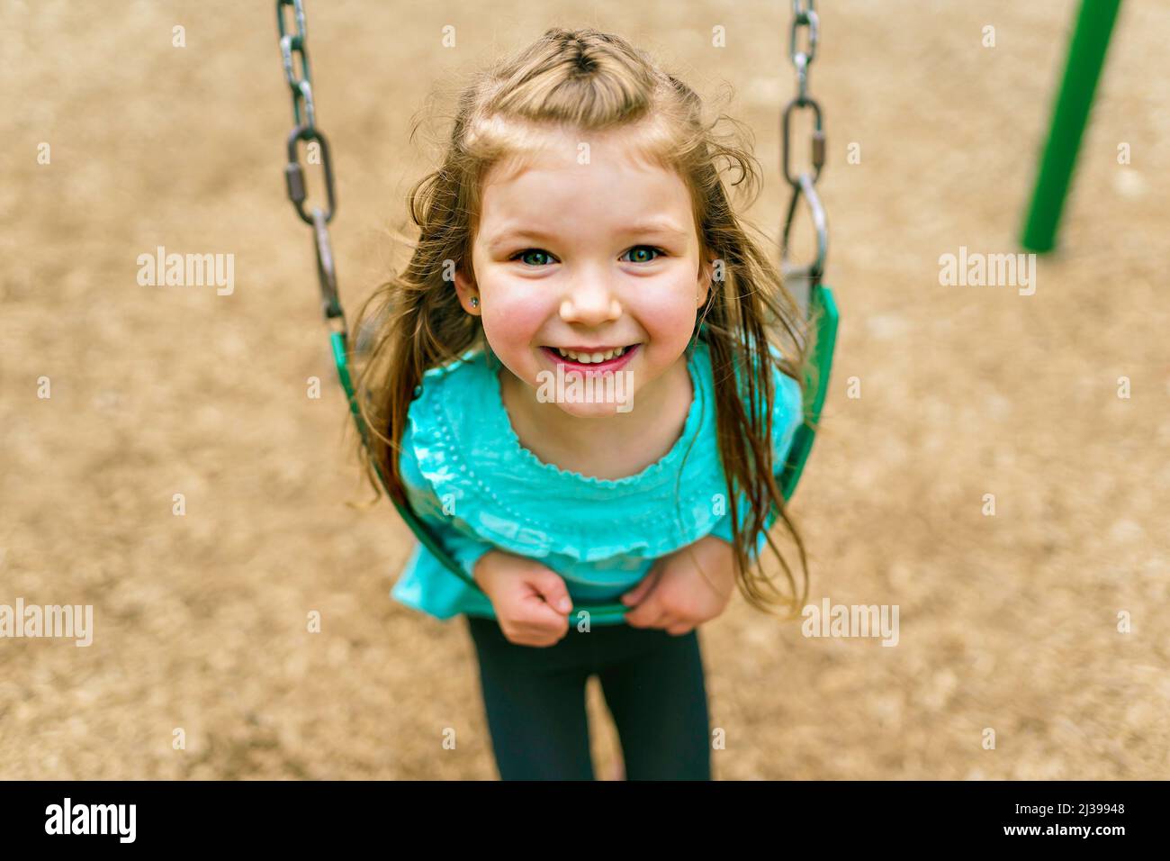 Happy little girl is playground having fun on swing Stock Photo