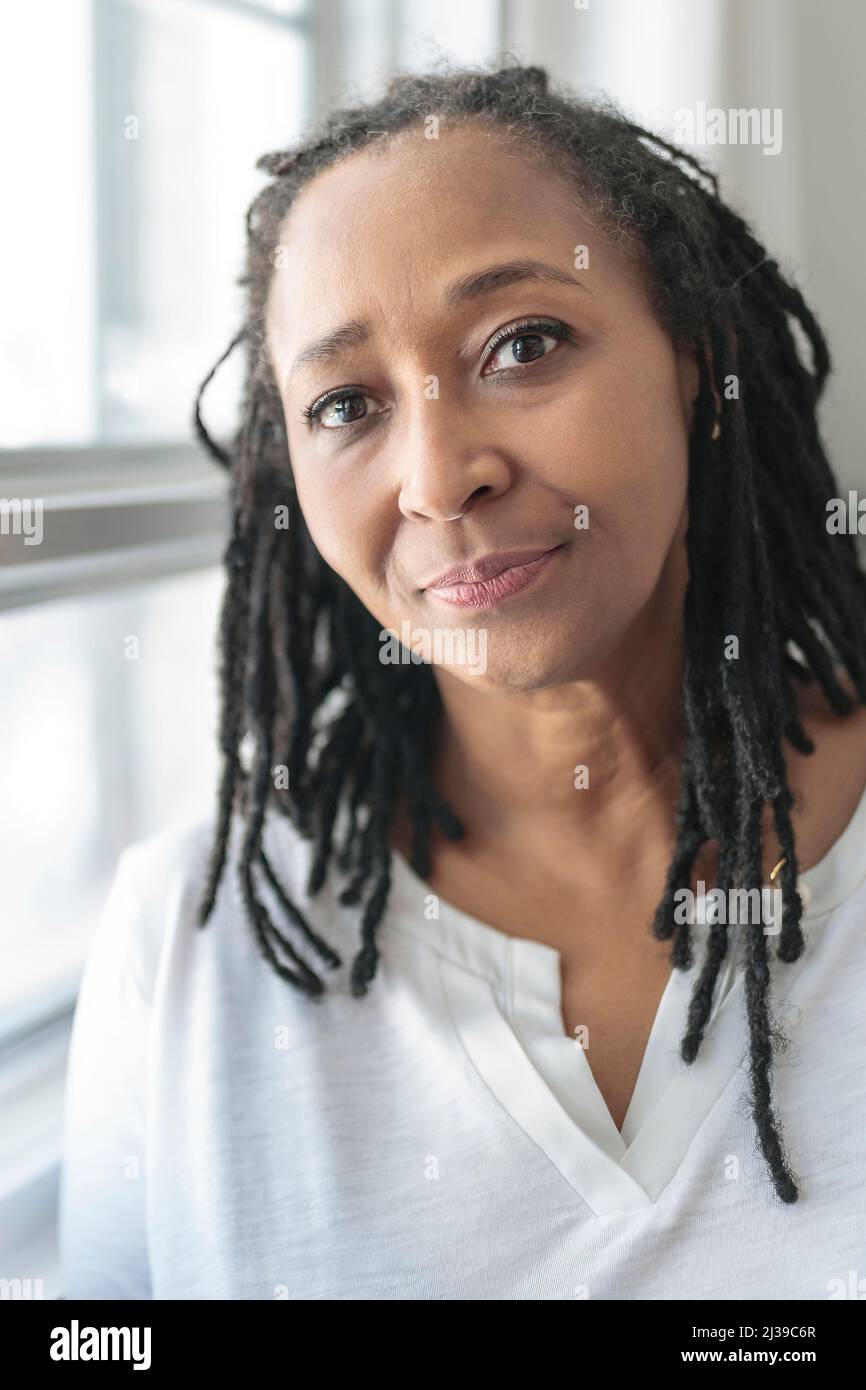 Portrait of an african woman in front of a white window Stock Photo - Alamy