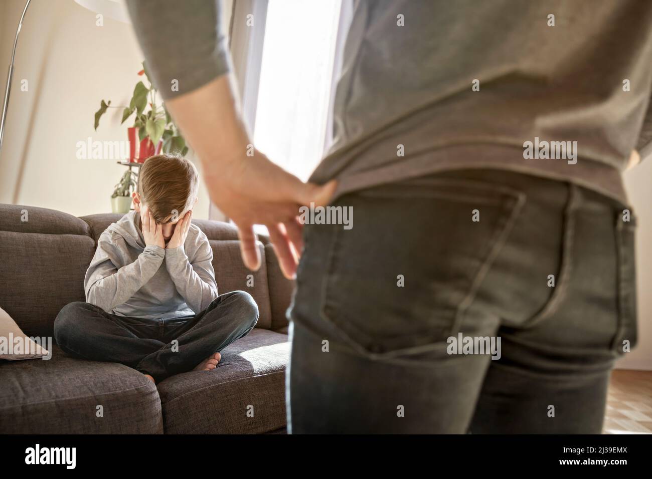 Sad child boy sit on the sofa with father in front of him with hard look Stock Photo