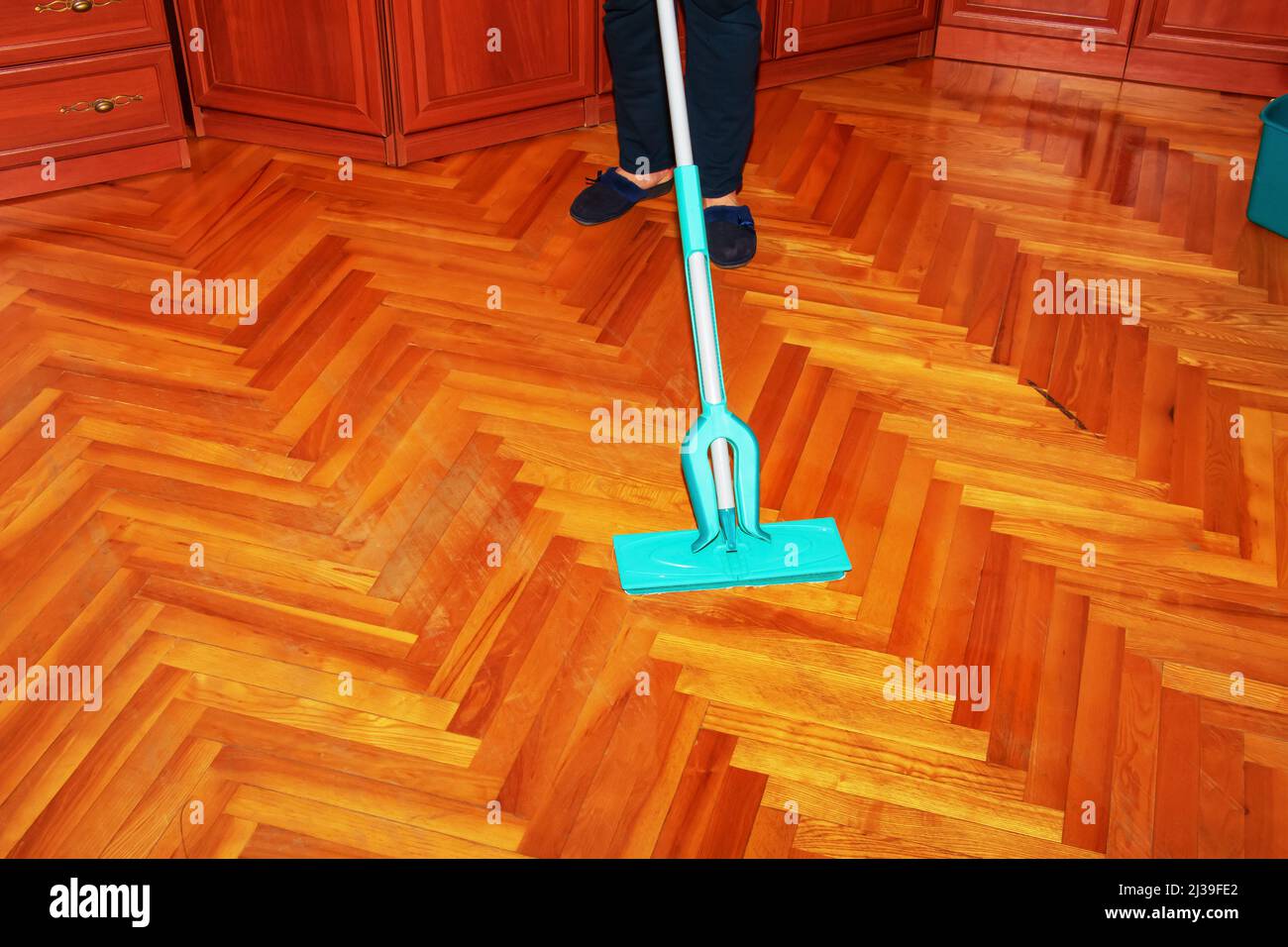 Mop your wood floor. A woman washes the parquet with a mop with a
