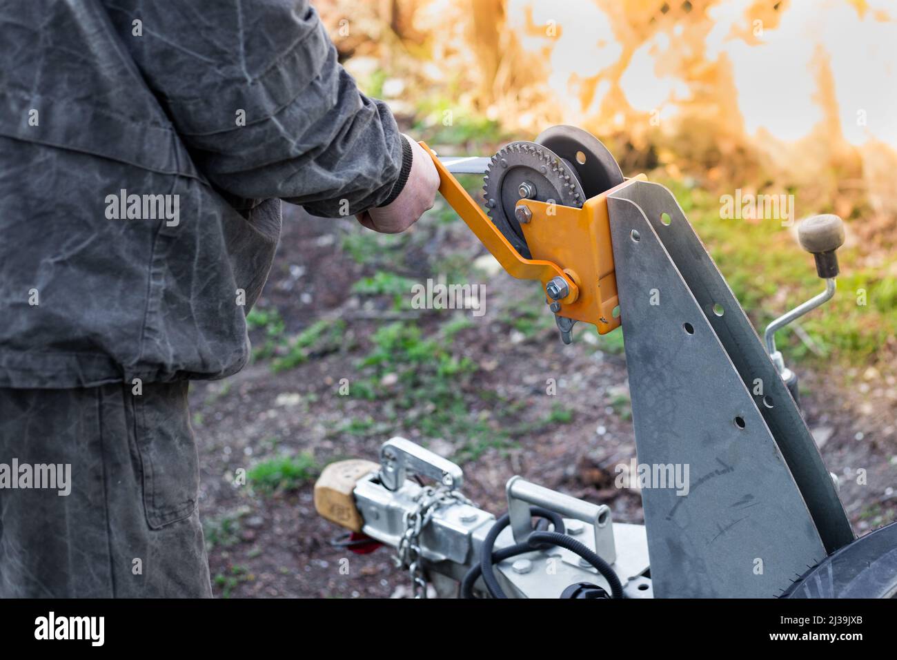 A man works with a winch on a trailer. Moving heavy loads, loading and unloading motor vehicles