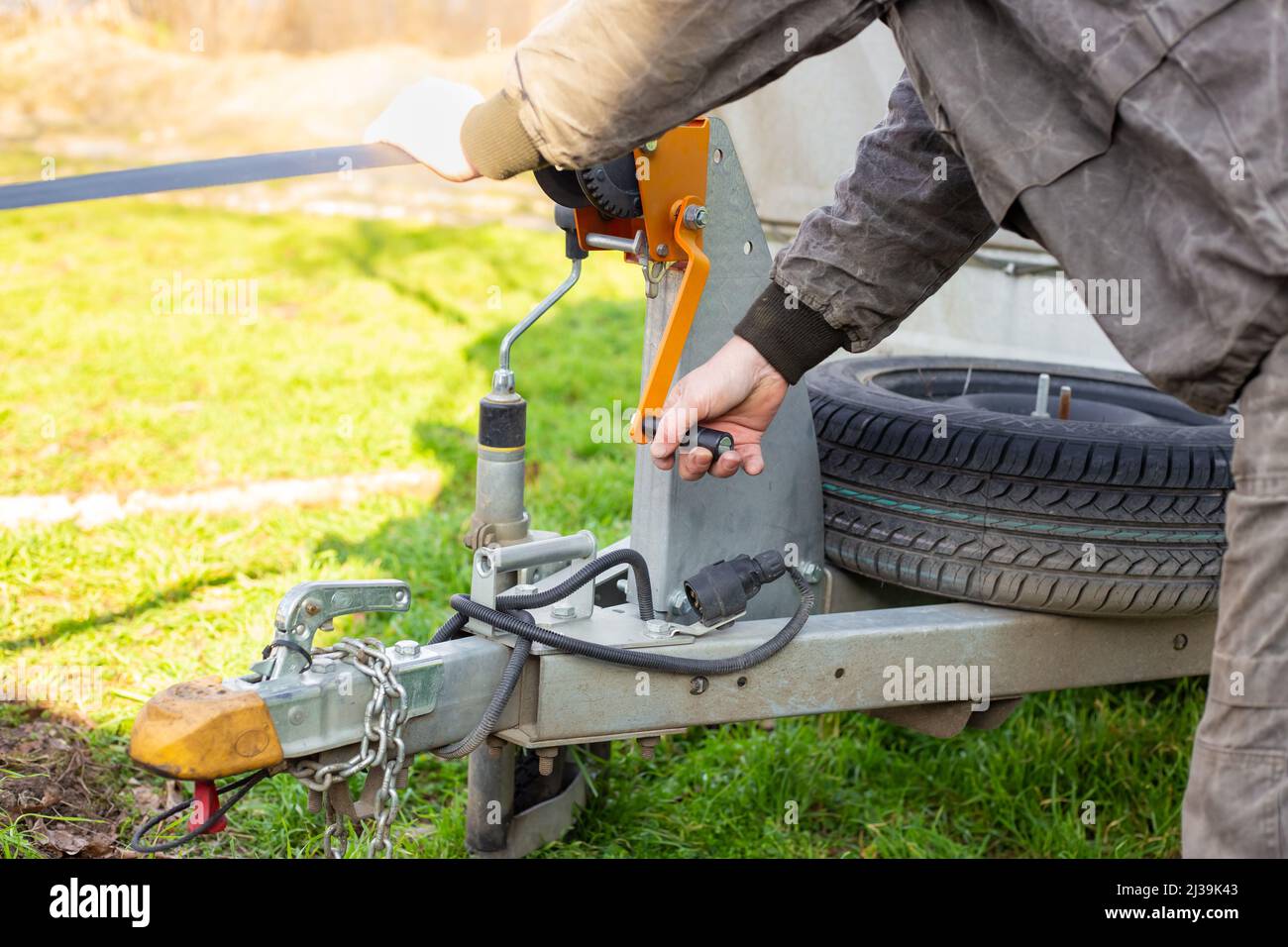 A man works with a winch on a trailer. Moving heavy loads, loading and