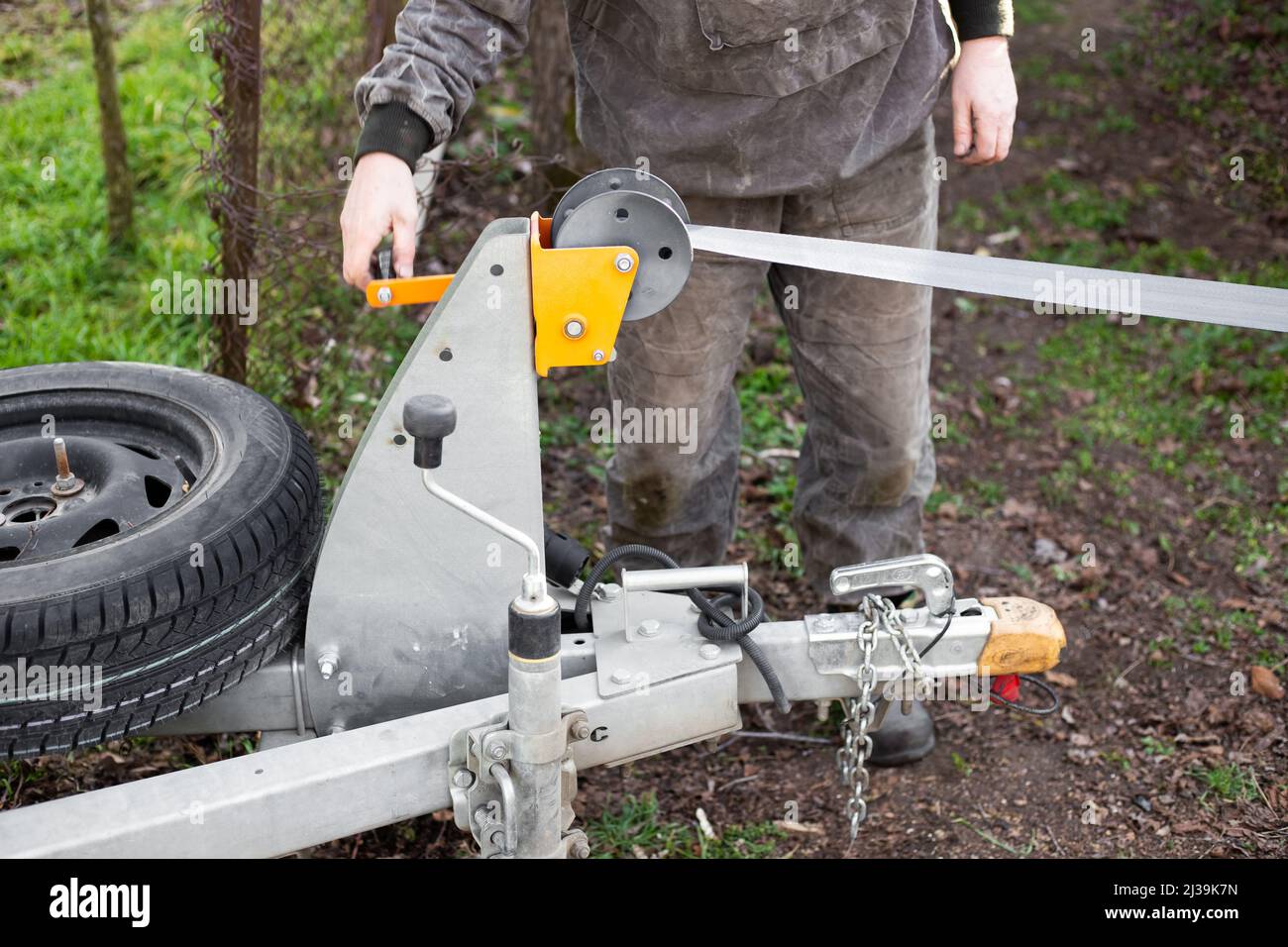 A man works with a winch on a trailer. Moving heavy loads, loading and