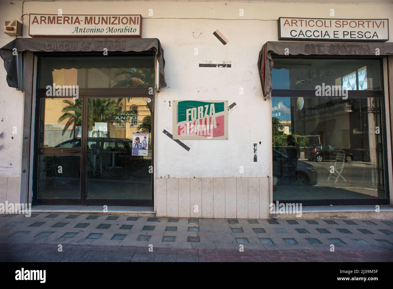 Gioiosa Jonica, Italy 03/07/2017: Forza Italia political poster between the windows of an armory and a hunting and fishing store. © Andrea Sabbadini Stock Photo
