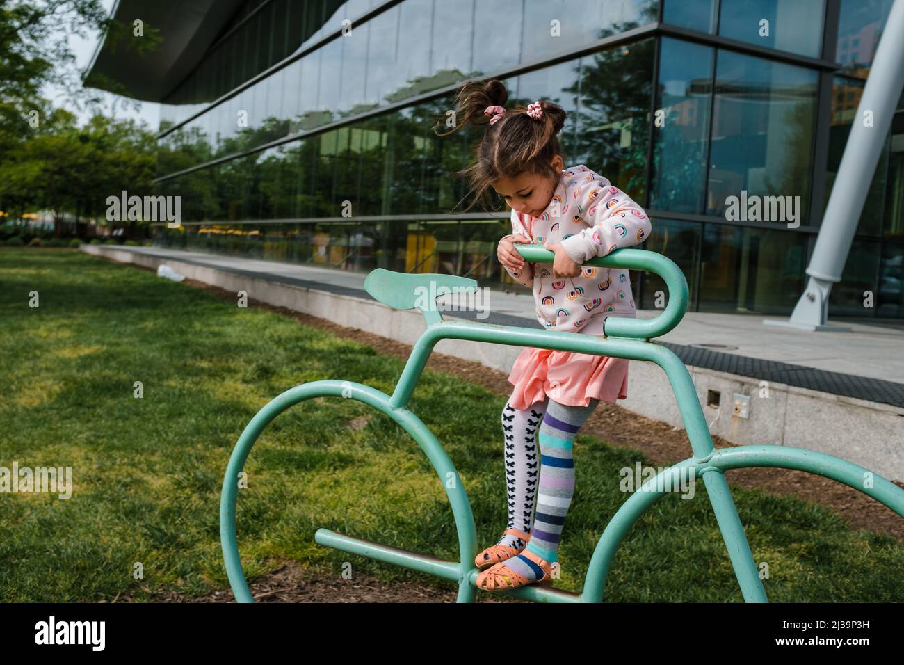 young girl playing on bike rack outside Stock Photo - Alamy