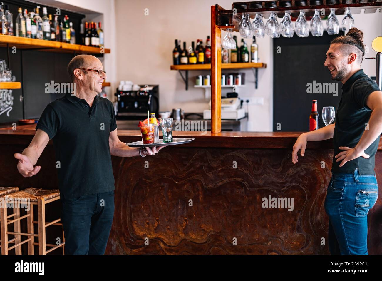 Co-workers serving drinks to their customers. Co-workers talking in their small business. Stock Photo