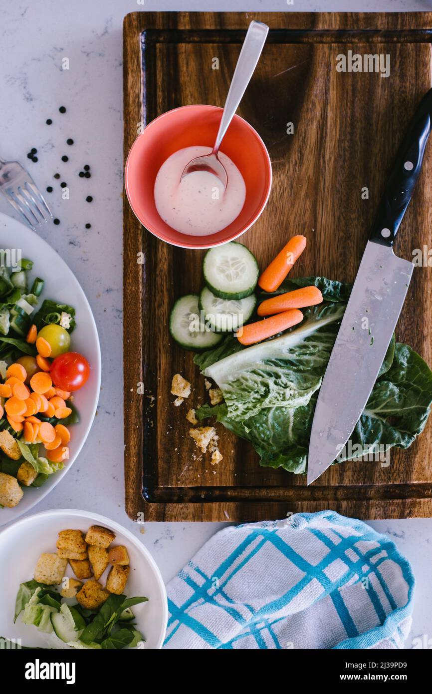 Making a salad with lettuce, cucumber and carrots on a cutting board Stock Photo