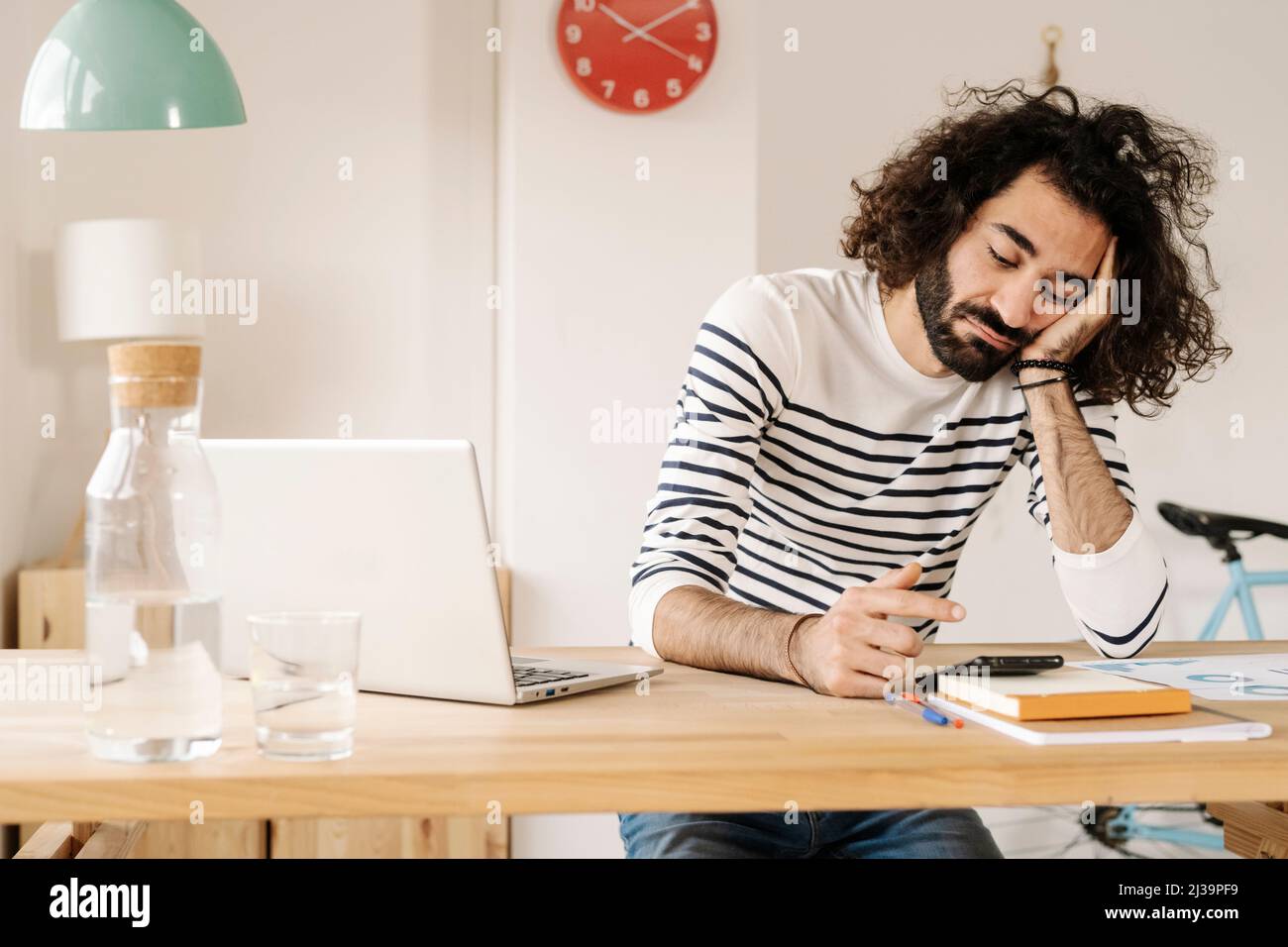 Bored young man using his cell phone at home office Stock Photo