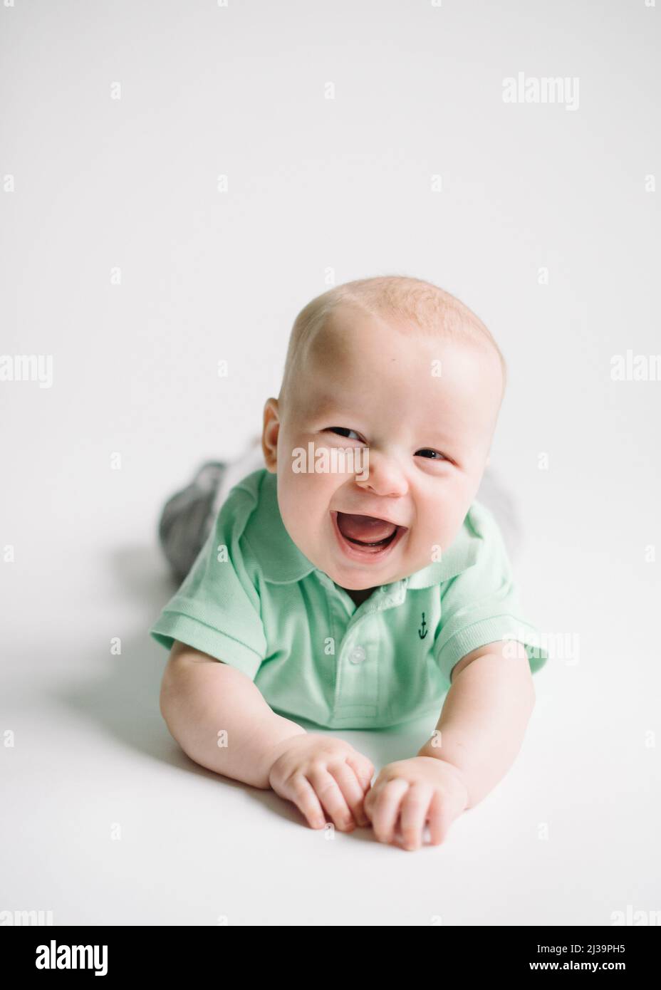 Happy Caucasian baby boy on white background wearing a green shirt Stock Photo