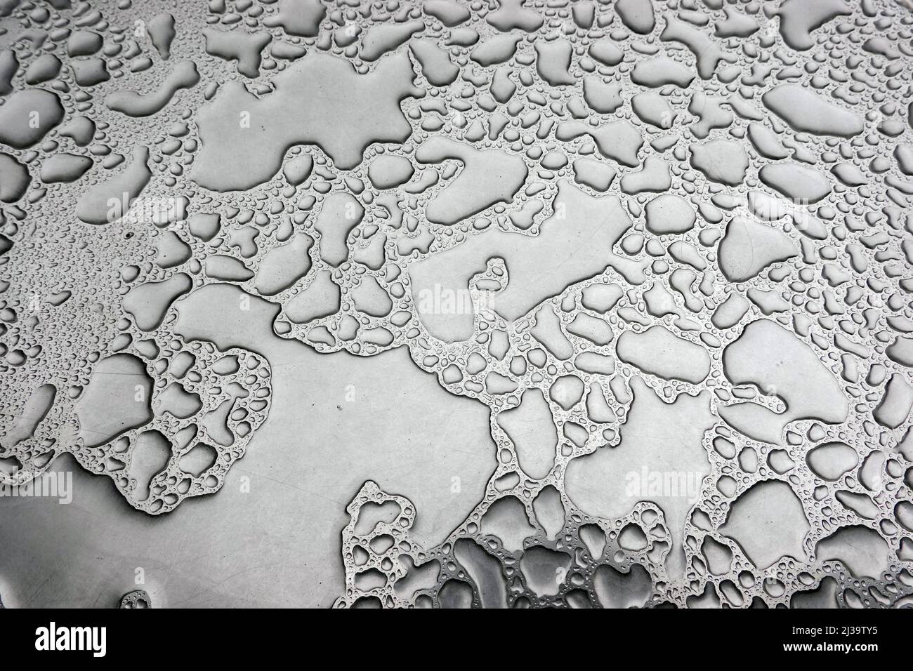 Regenwasser auf einem Bistrotisch bilden ein abstraktes Muster Stock Photo