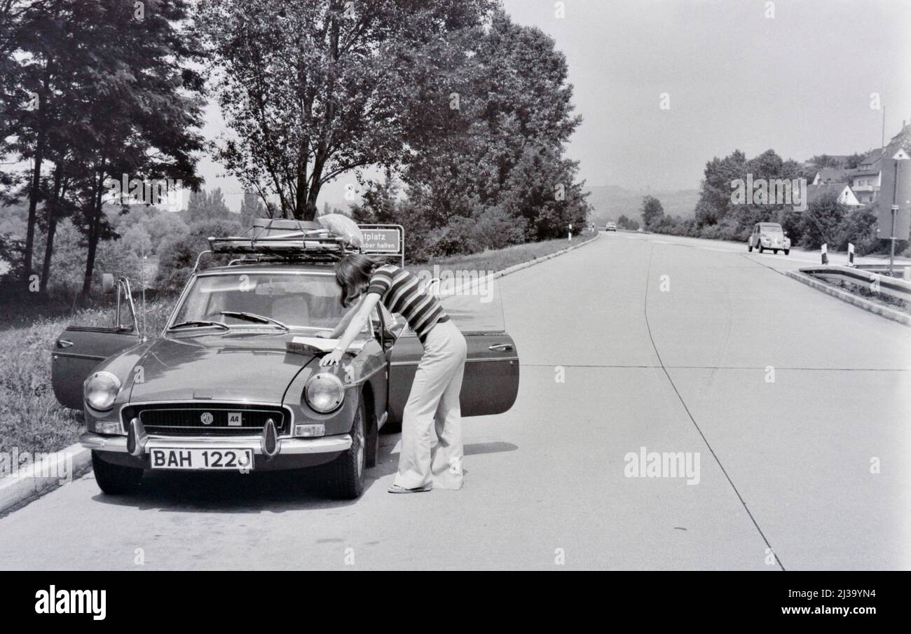 vintage image of woman reading map on english car bonnet germany 1970's Stock Photo