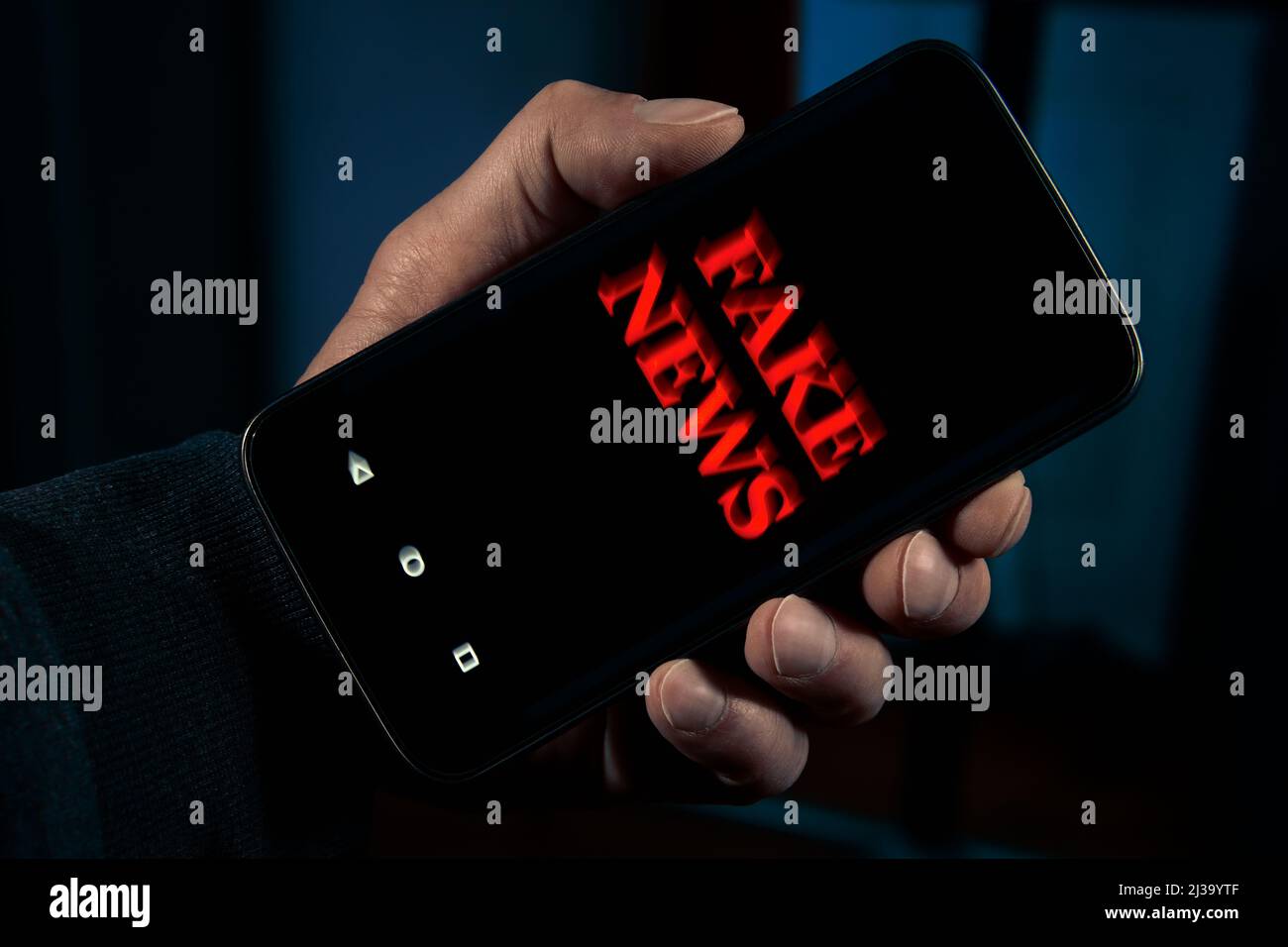 Person holding a smartphone with fake news information media Stock Photo