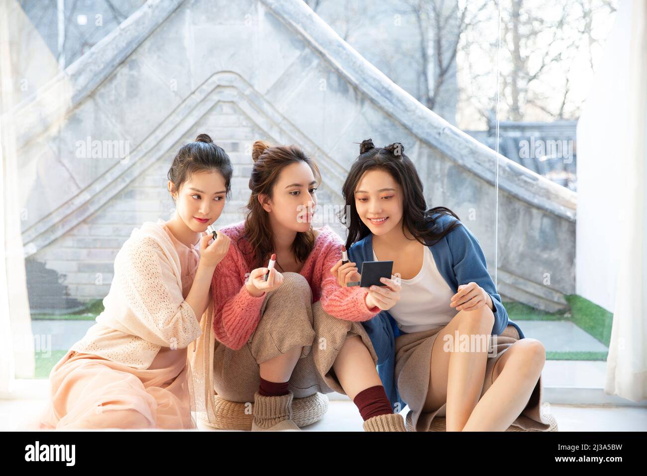 Beautiful young fashionable Chinese ladies try lipstick in their spare time - stock photo Stock Photo