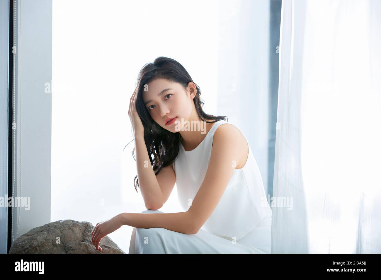 A young slim attractive ethnic chinese asian woman girl wearing white  underwear applying makeup to her face and eyes in a bathroom at home UK  Stock Photo - Alamy