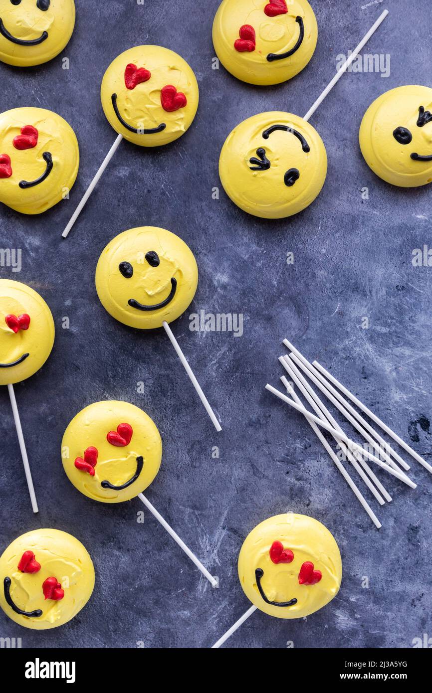 Several smiley face emoji merengue cookies with lollipop sticks. Stock Photo