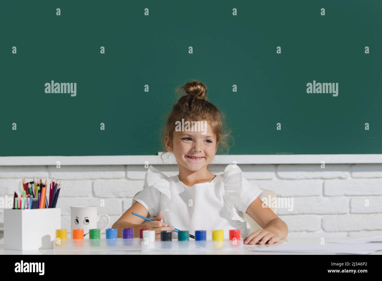 Cute little girl child painting with paints color and brush. Cute
