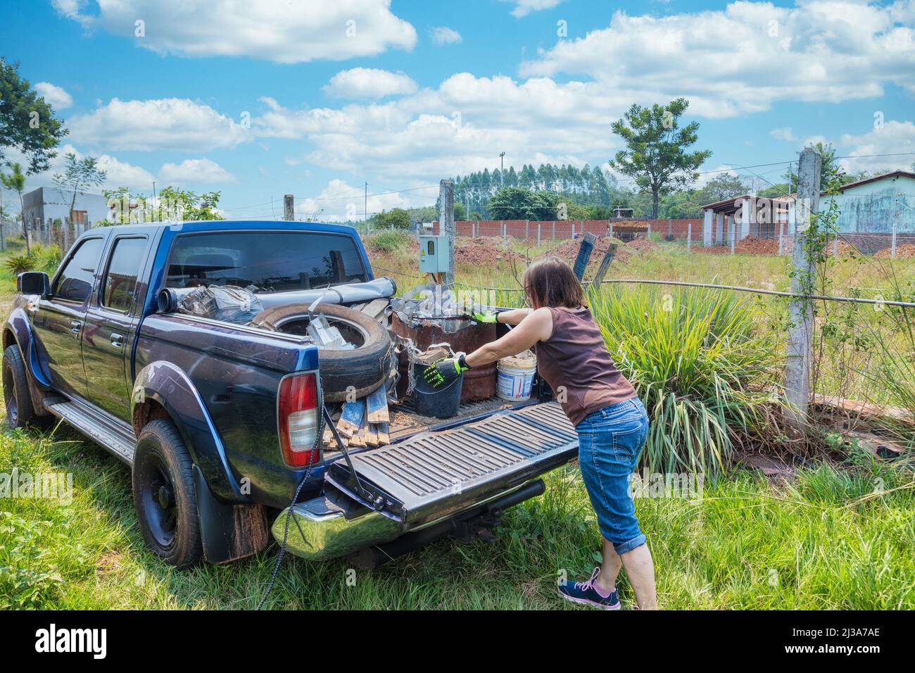 A woman loads garbage onto a pickup truck in Paraguay. Stock Photo