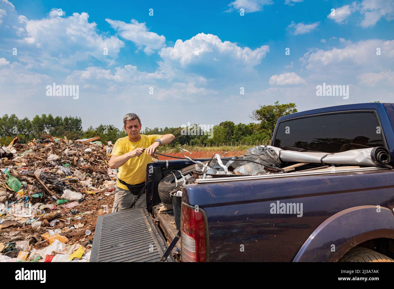 A man unloads his garbage from a pickup truck at a garbage dump in Paraguay. Stock Photo
