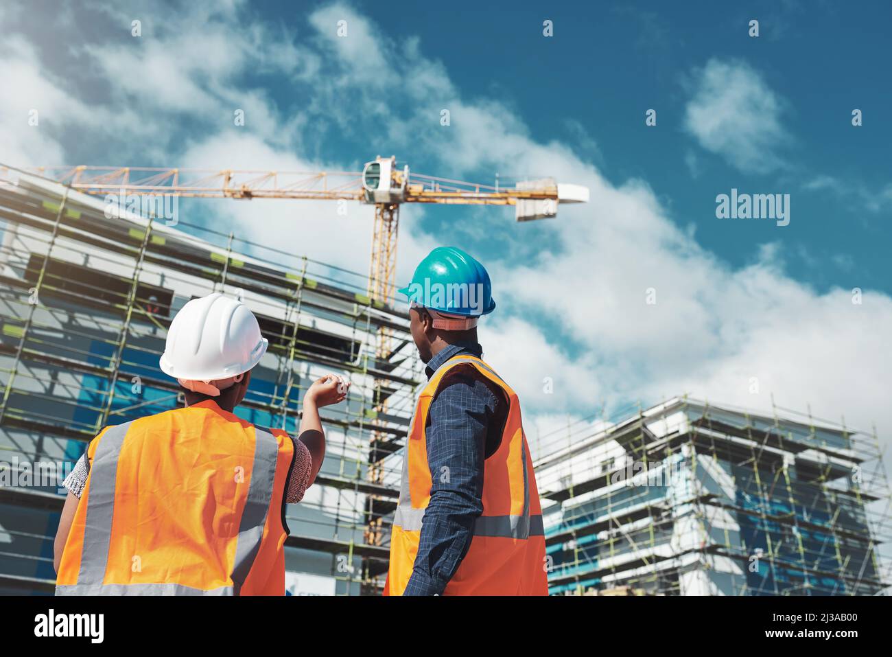 Their reputation is about to raise the roof. Shot of a young man and woman assessing progress of the building at a construction site. Stock Photo
