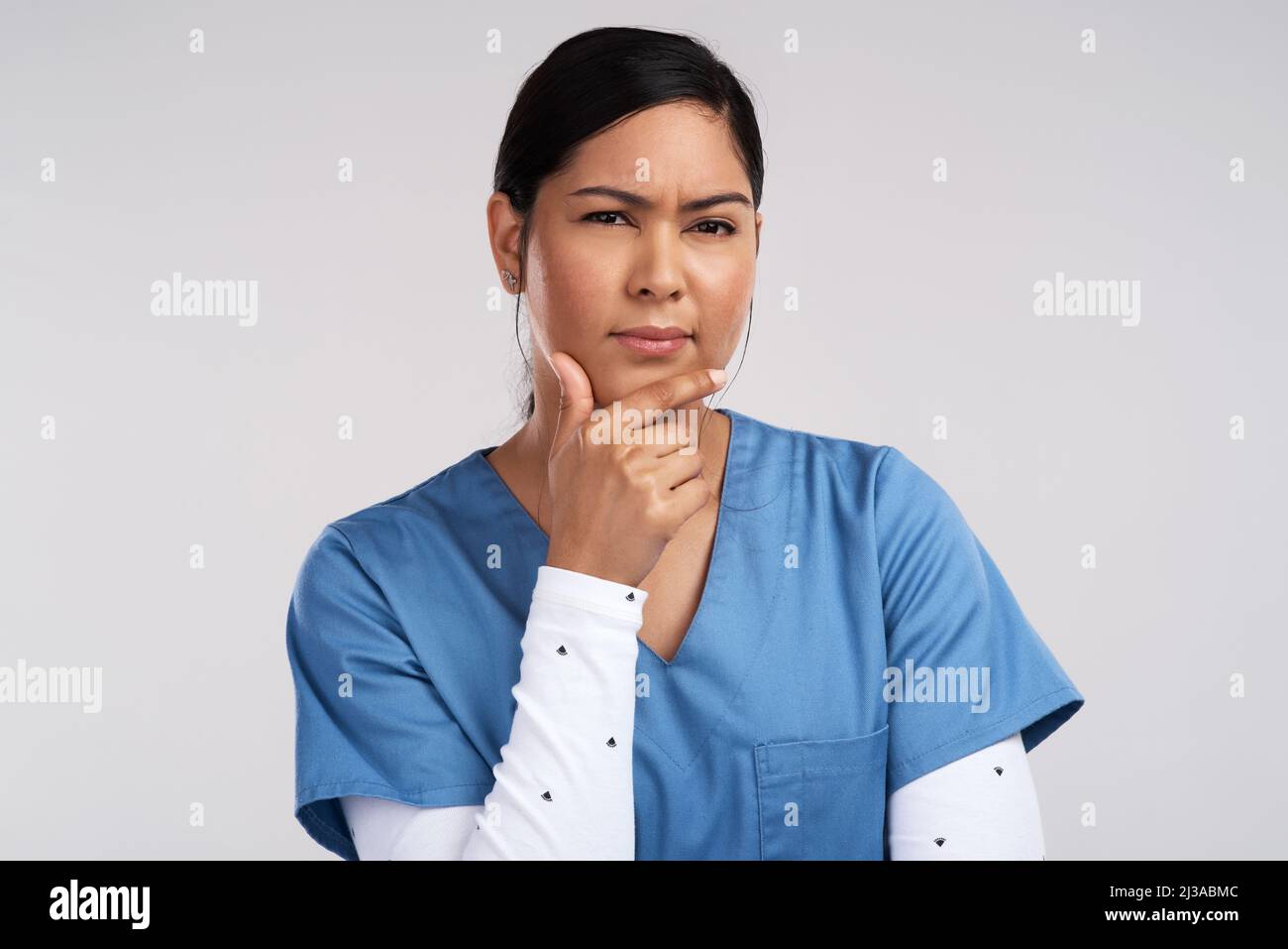 Bring your best wounds, dress them up just for you. Portrait of a young beautiful doctor deep in thought against a white background. Stock Photo