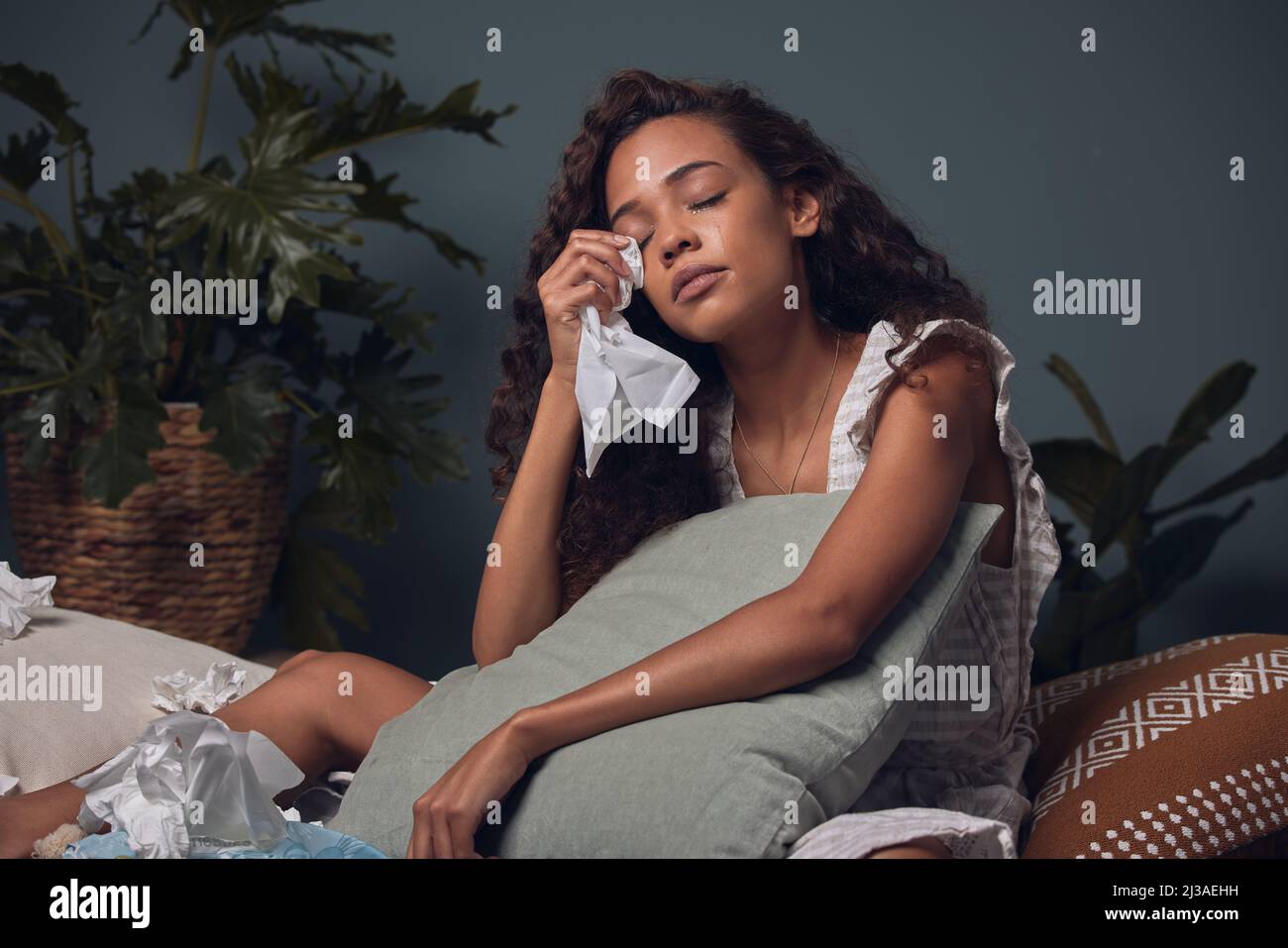 Let it out and let it go.... Shot of a young woman wiping her tears with a tissue while sitting at home alone. Stock Photo