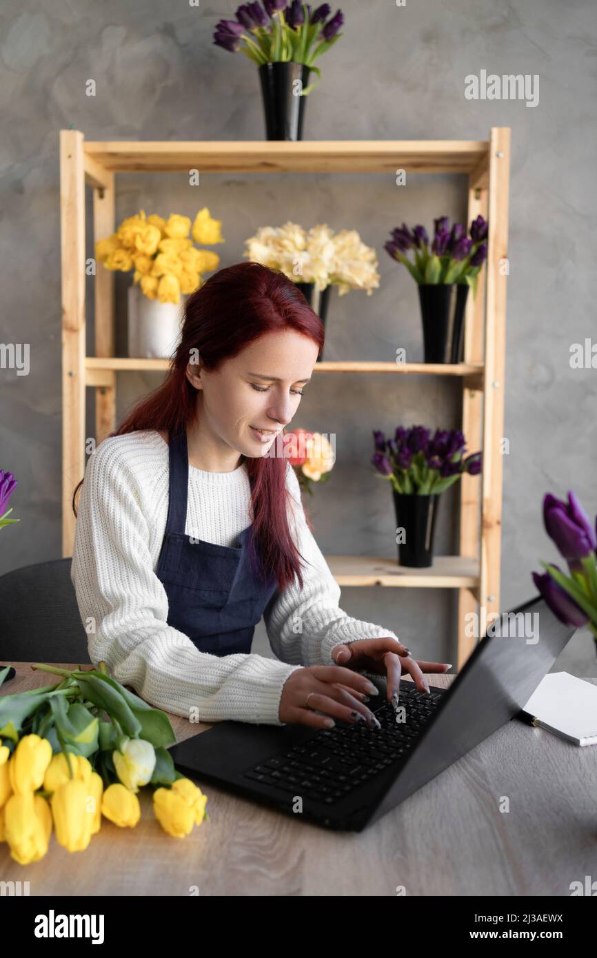 Portrait florist in an apron working in her own flower shop, using a