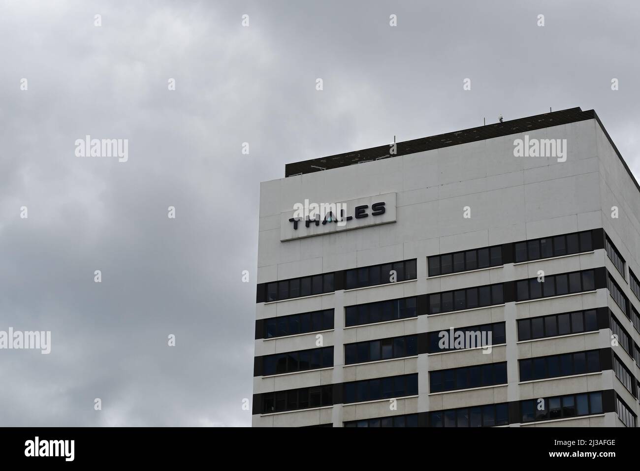 Grimy Thales logo on a white skyscraper, during a cloudy day Stock Photo