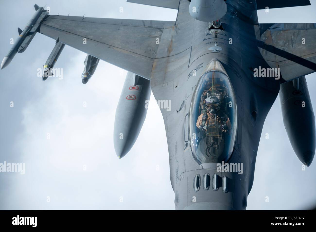 A U.S. Air Force F-16 Fighting Falcon pilot receives fuel from a U.S. Air Force KC-135 Stratotanker over the U.S. Central Command area of responsibility March 24th, 2022. The F-16 Fighting Falcon delivers airpower and showcases Ninth Air Force (Air Forces Central)’s commitment to security and stability in the USCENTCOM AOR. (U.S. Air Force photo by Staff Sgt. Frank Rohrig) Stock Photo