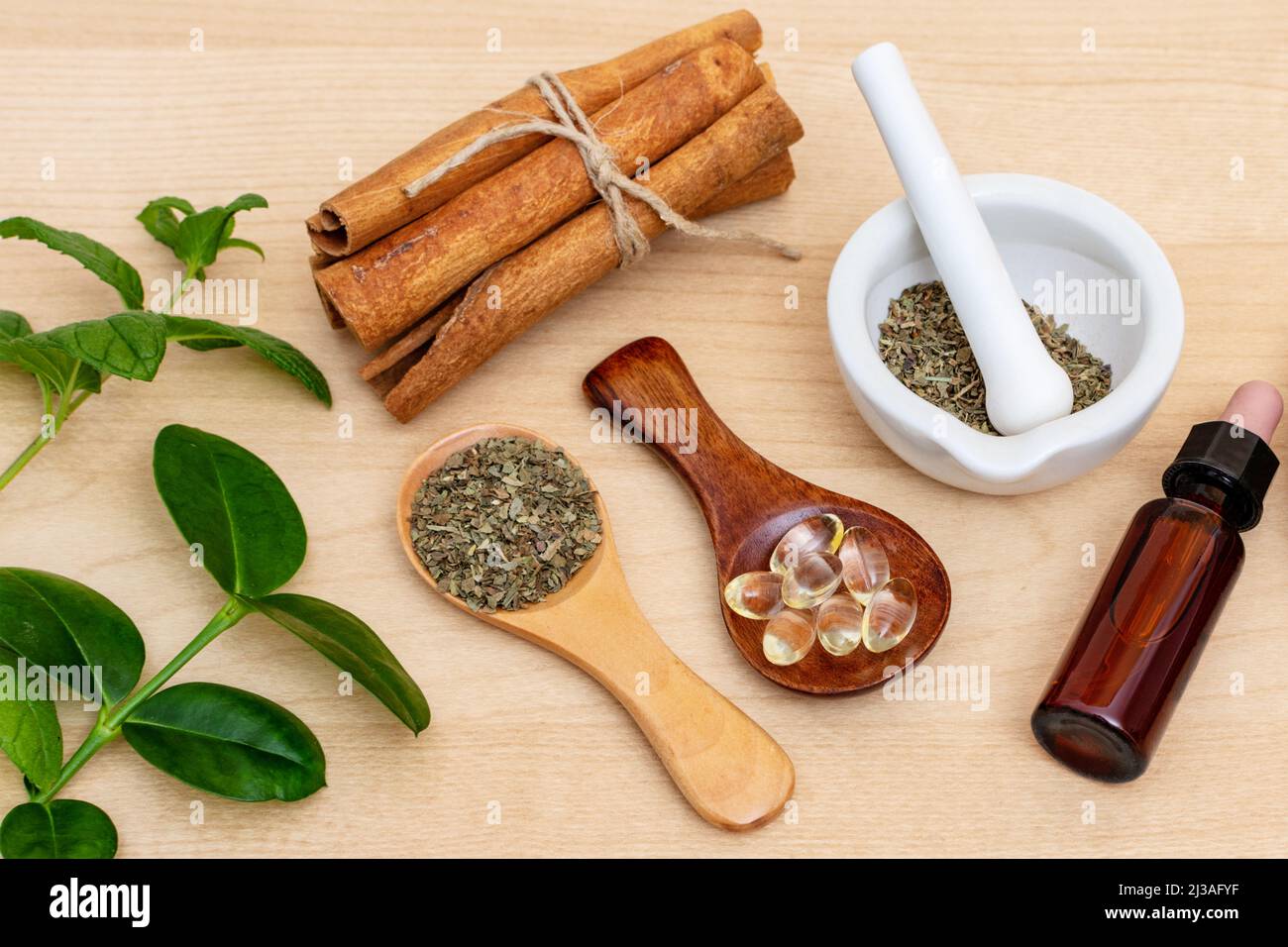 A top view of fresh herbs from the garden and the different types of oils for massage and aromatherapy on wooden table Stock Photo