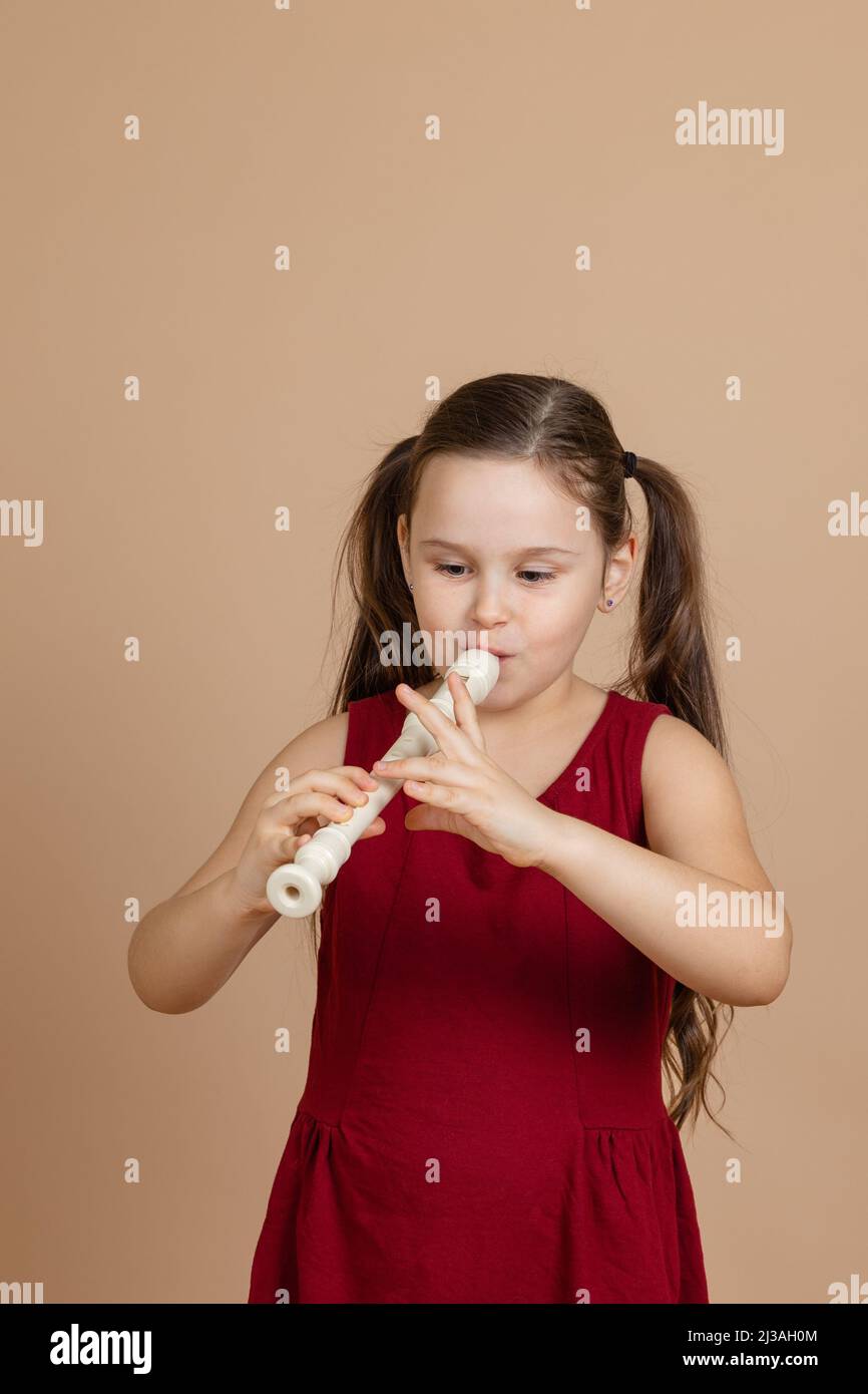 Girl in red dress play with pleasure melody on flute, blowing air into