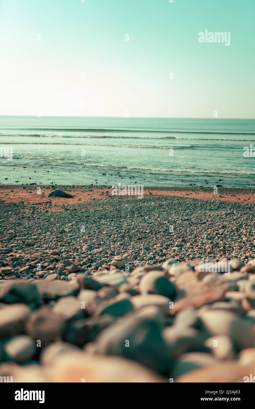 A vertical shot of rocky beach in background of ocean waves in Strandhill Stock Photo