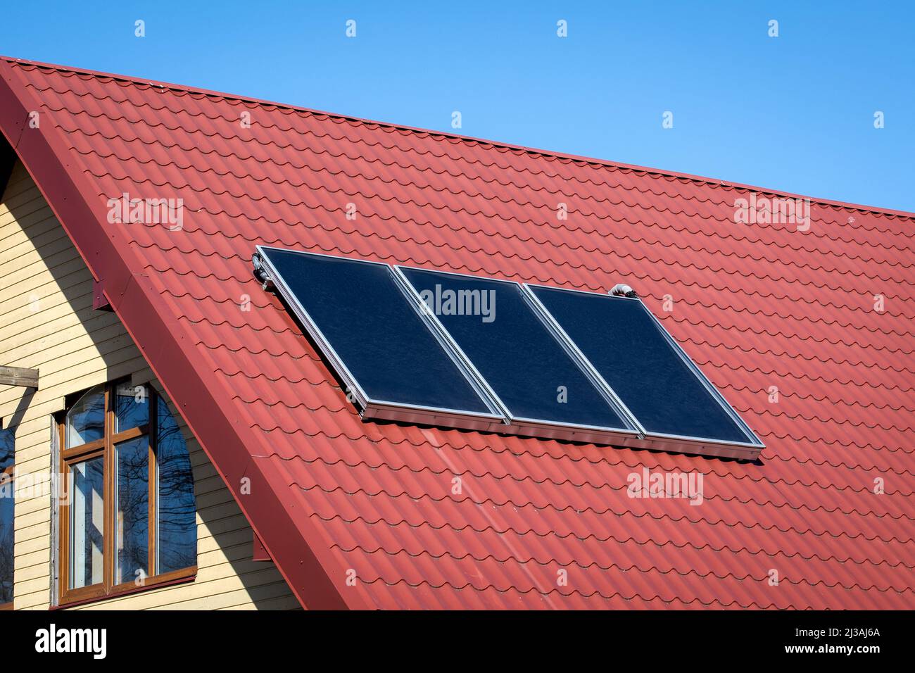 Solar energy. Water solar collector on a red metal roof Stock Photo - Alamy