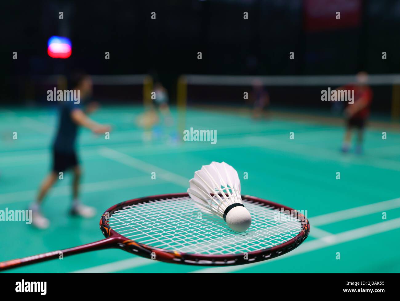 shuttlecock on green badminton playing court with player in background Stock Photo
