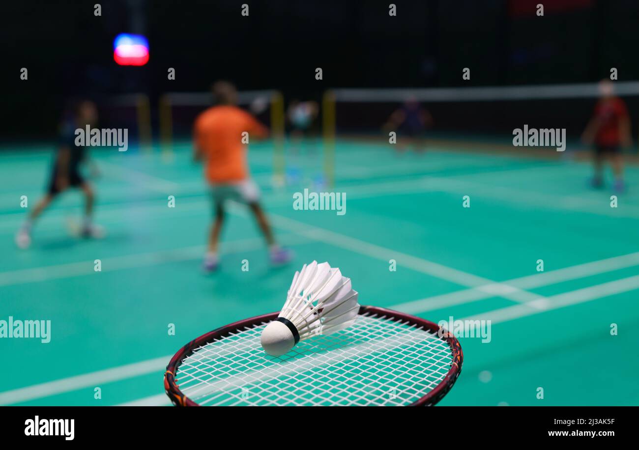 shuttlecock on green badminton playing court with player in background Stock Photo