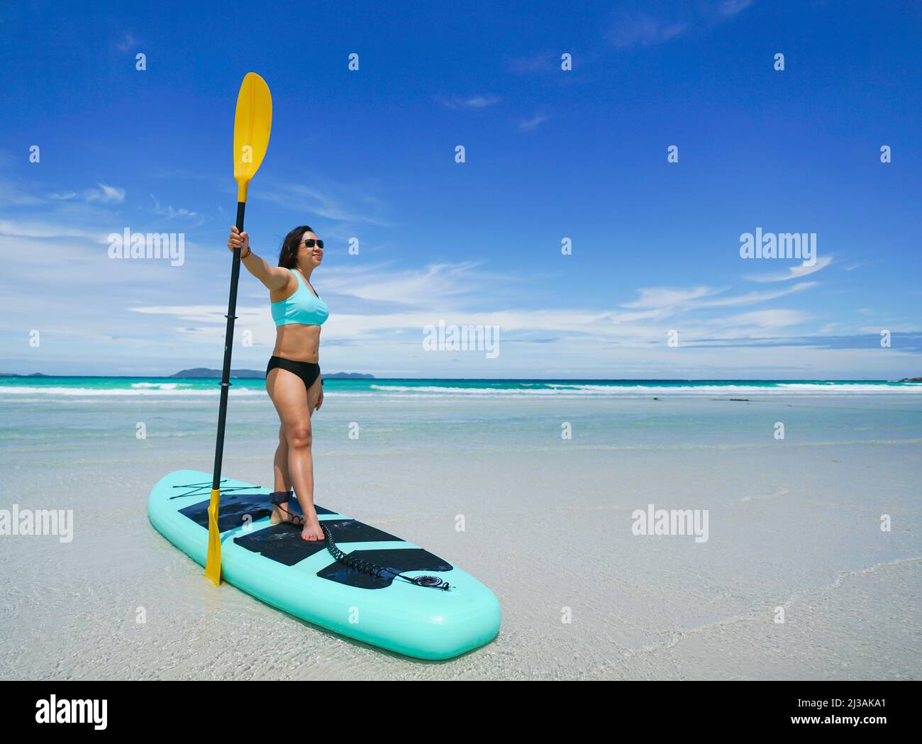 woman on sup board or paddle board at the beach Stock Photo