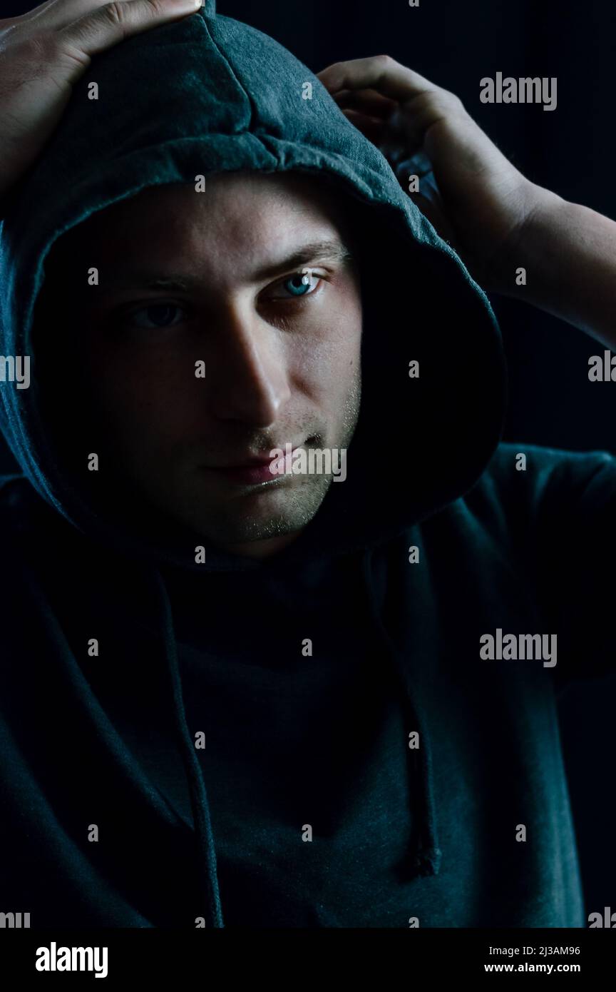 Portrait of a young man adjusting the hood on his head with his hands Stock Photo