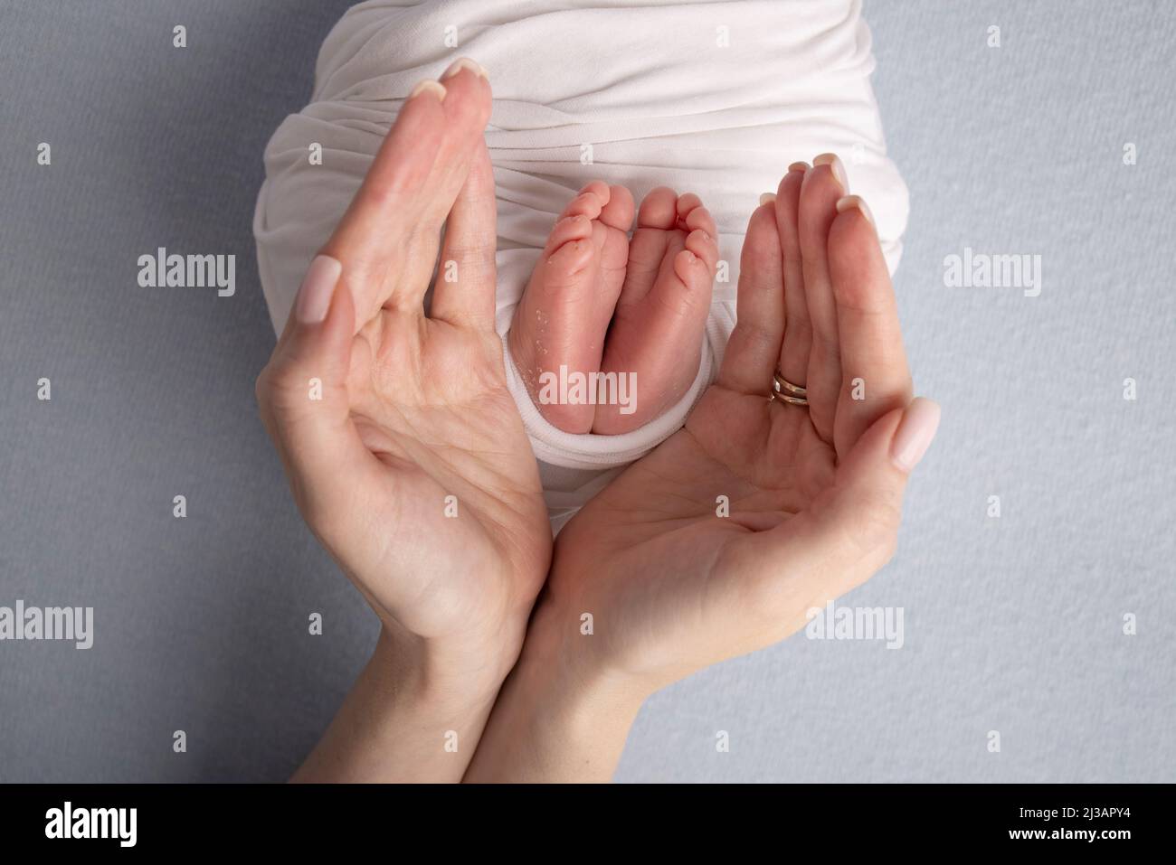 The palms of the father, the mother are holding the foot of the newborn
