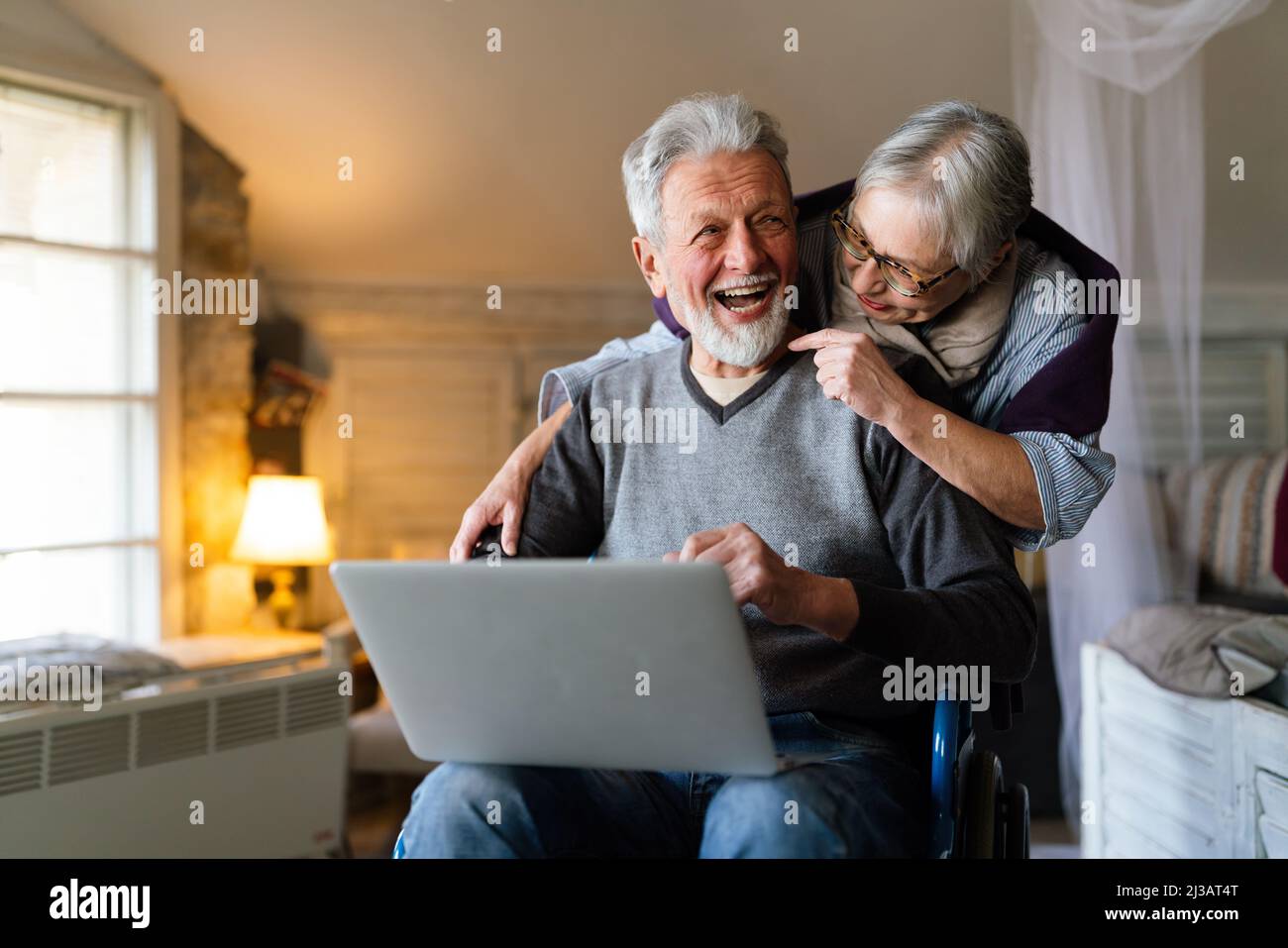 Happy senior couple using notebook at home and having fun together. Technology people concept Stock Photo