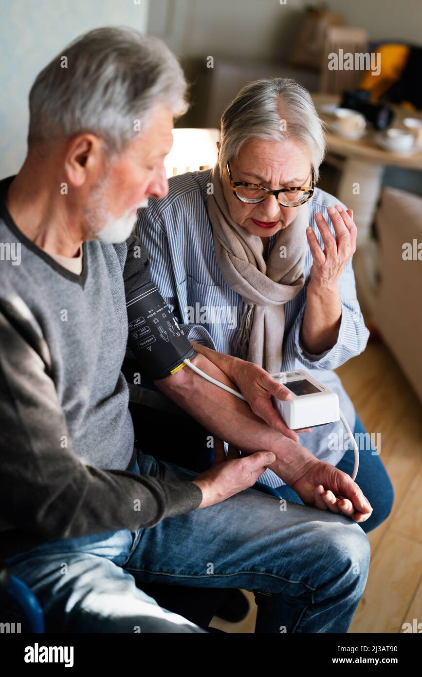 Senior couple at home measuring blood pressure. Home monitoring people healthcare concept Stock Photo