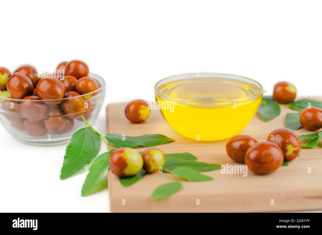 Bowl of jojoba oil. Jojoba oil and fresh jojoba fruit on wooden table Stock Photo